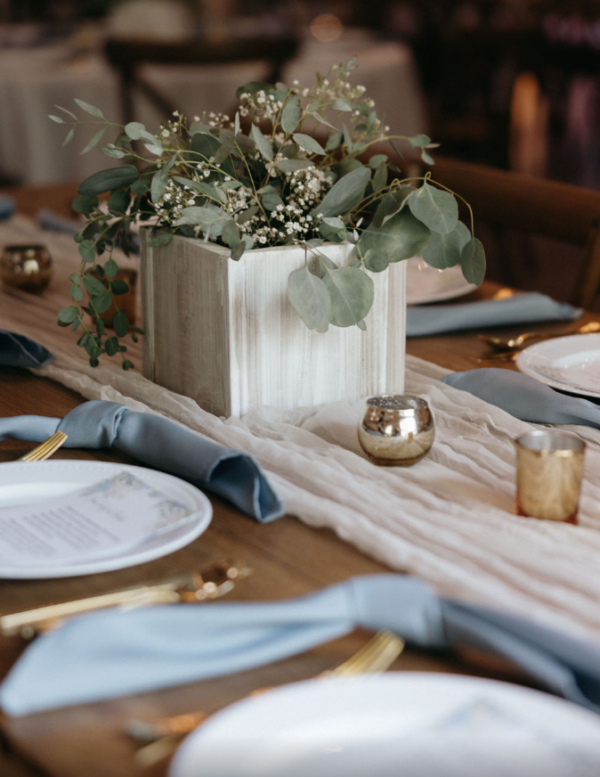 Wedding reception details with gold, florals and blue napkins